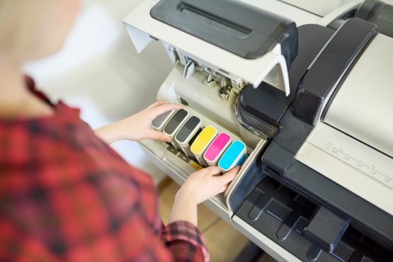 mujer cambiando cartuchos cmyk de impresora